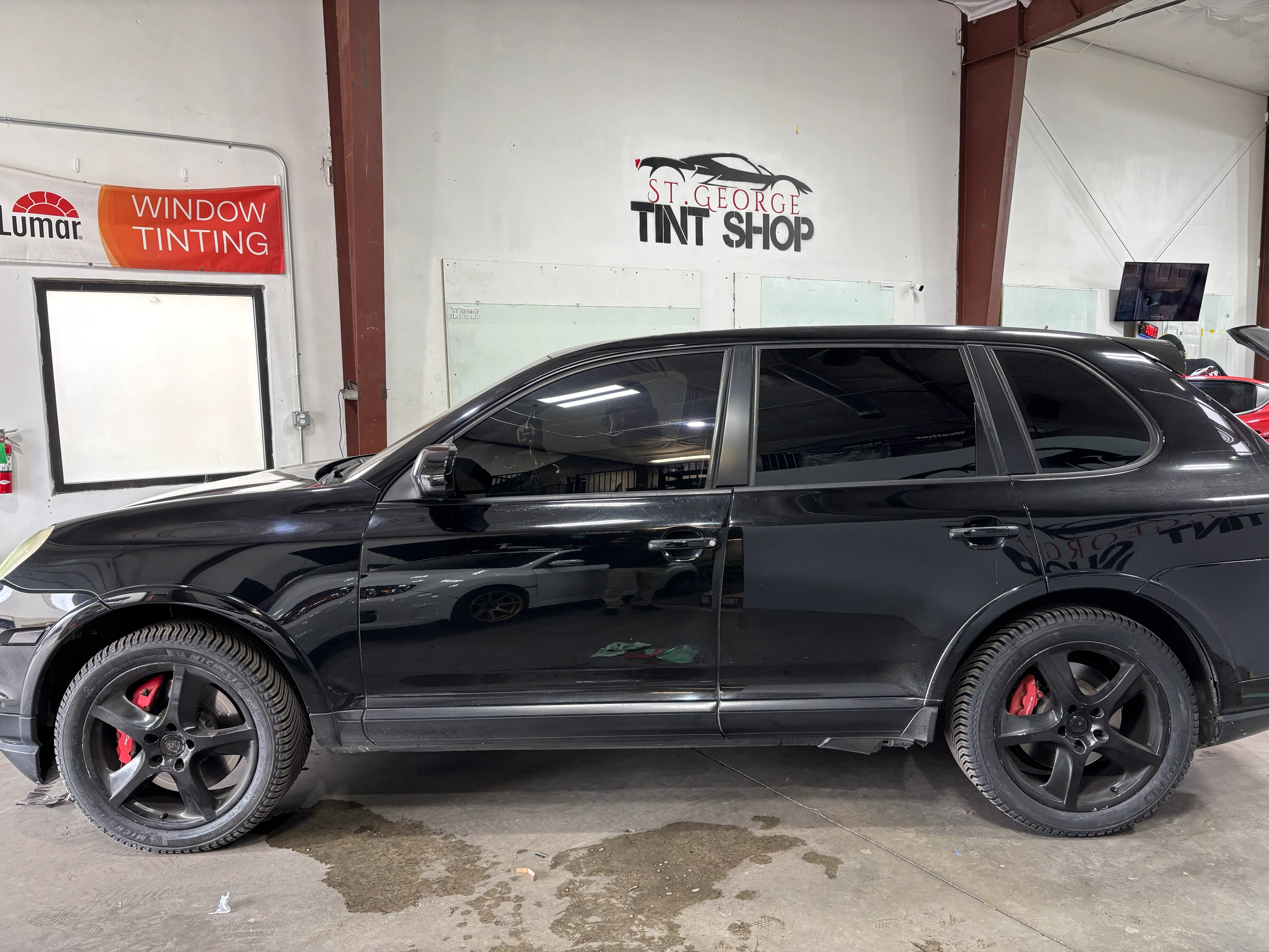 Dark tinted windows on a black Porsche Cayenne SUV, showcasing professional ceramic tinting in St. George, Southern Utah.