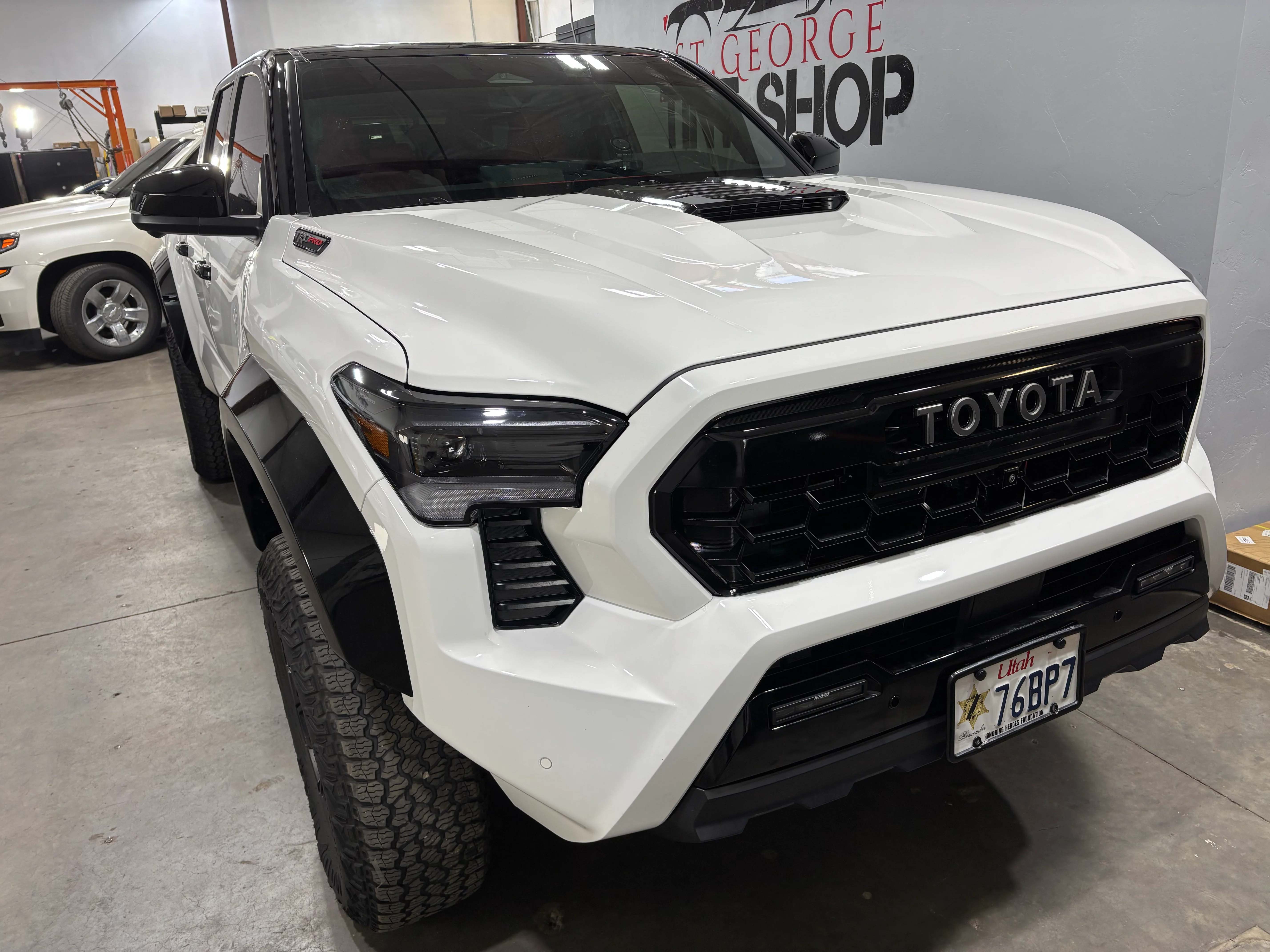 Front view of a white Toyota truck with dark window tint and black accents, expertly installed at a professional shop in St. George, Utah.