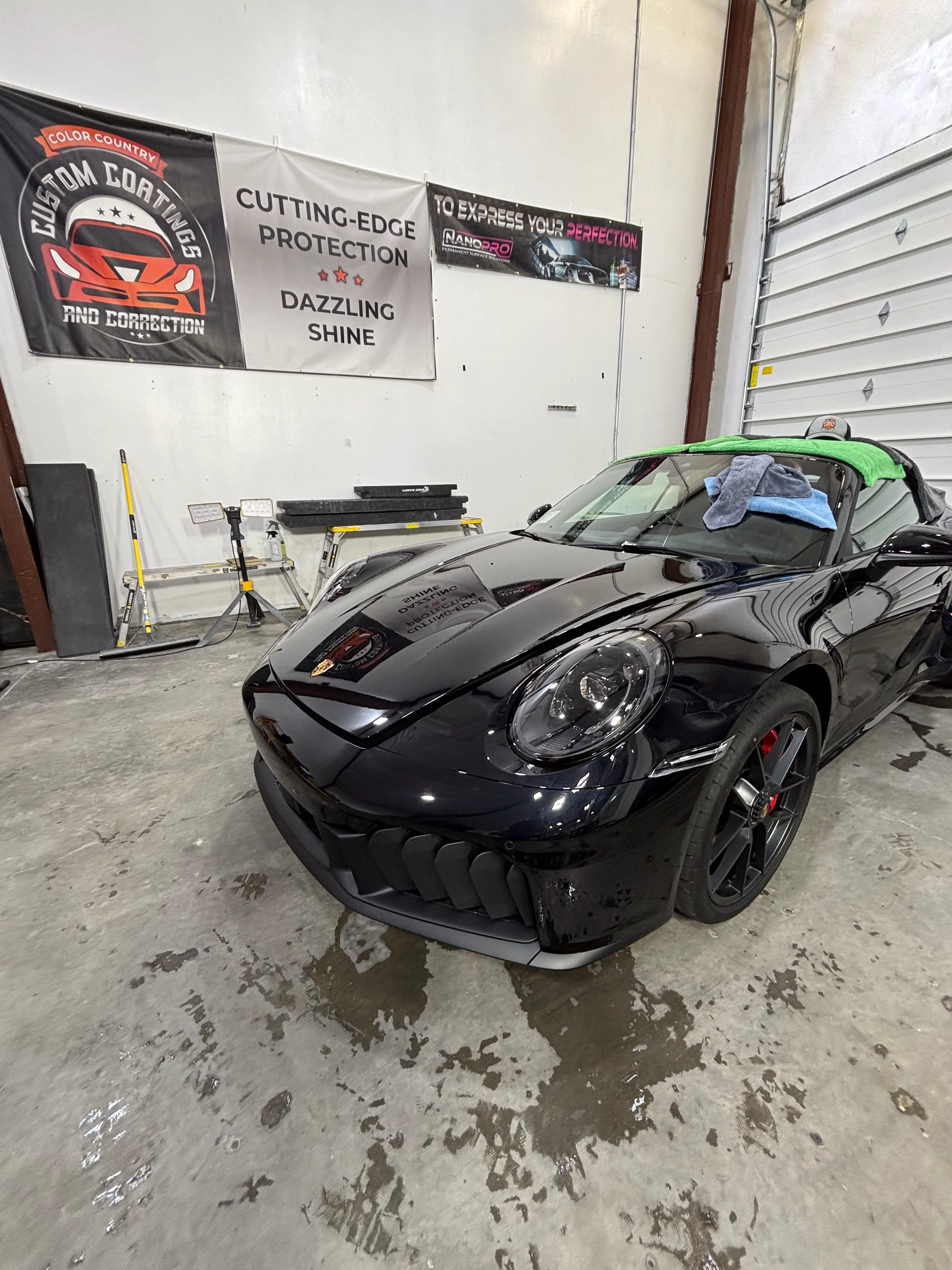 Sleek black Porsche sports car undergoing professional PPF and ceramic window tinting in a St. George, Southern Utah shop.