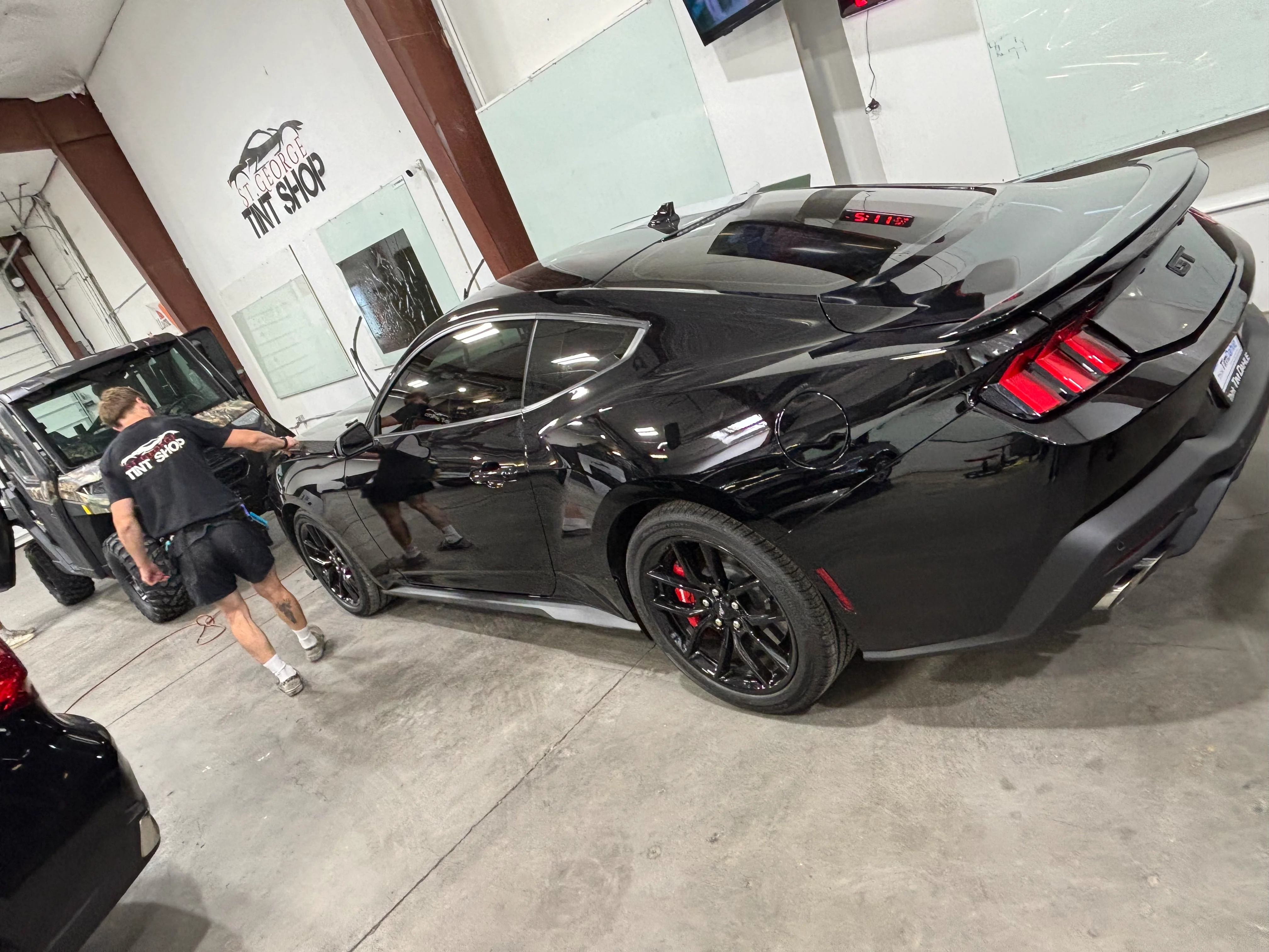 Professional ceramic window tint being applied to a sleek black Ford Mustang GT at a tint shop in St. George, Utah.