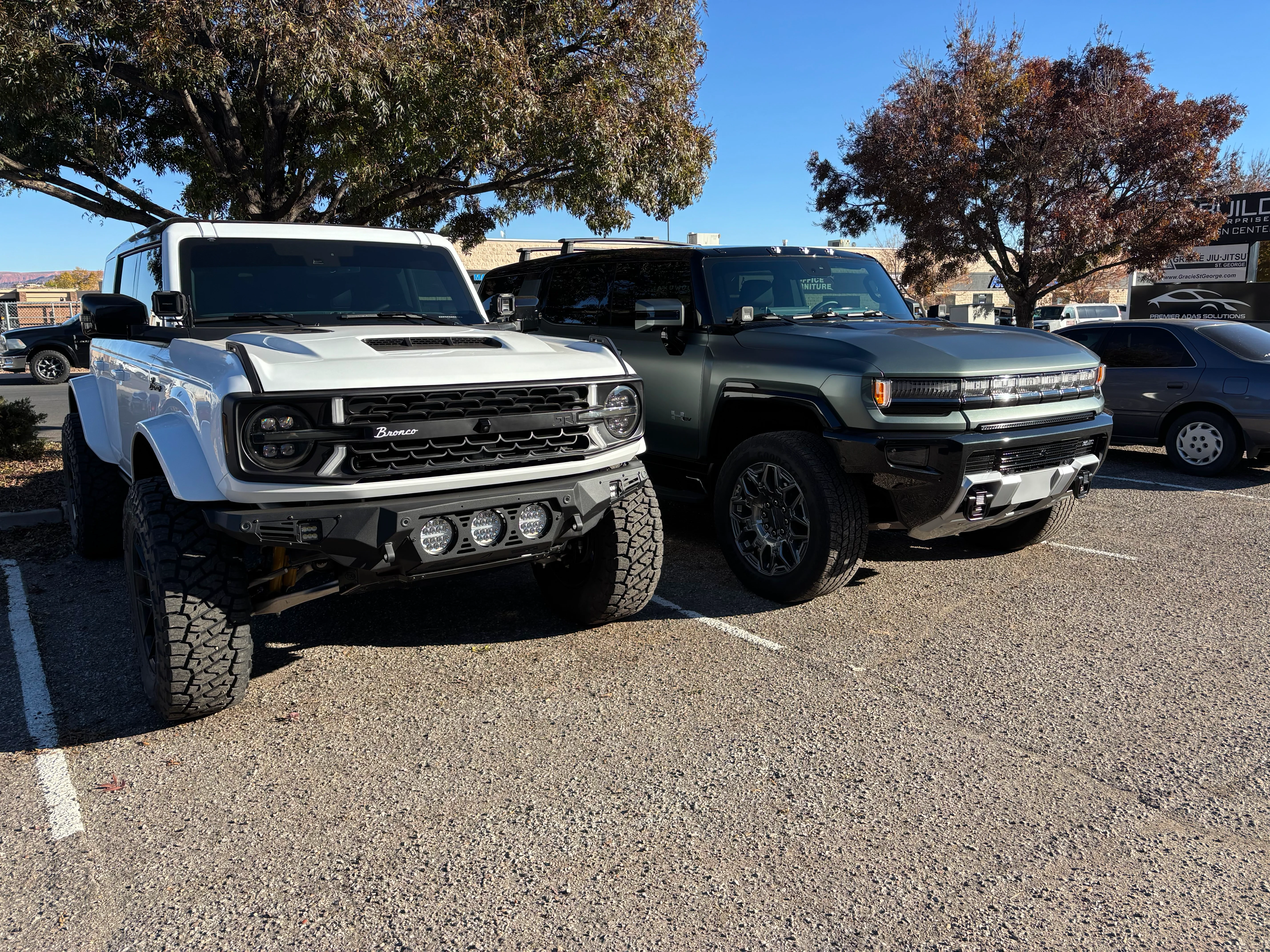 A white Ford Bronco and a gray Hummer EV, both with professional window tint, parked in St. George, Southern Utah.