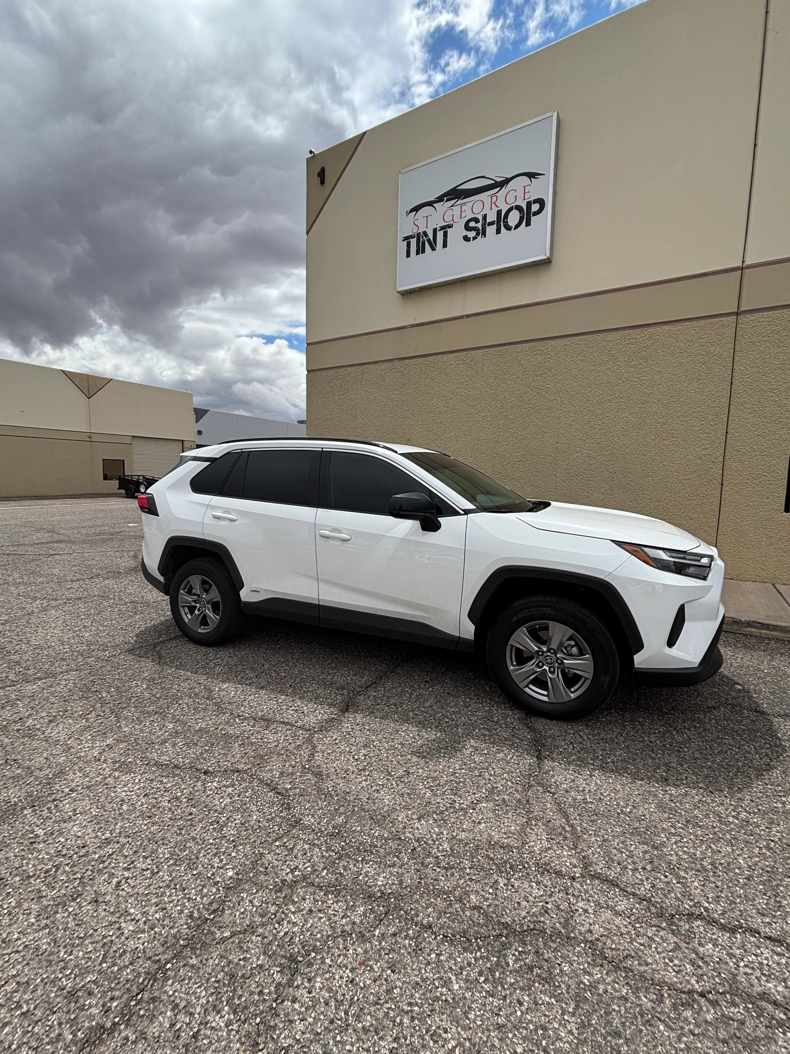 White Toyota RAV4 SUV with dark ceramic window tint parked outside St. George Tint Shop in Southern Utah.