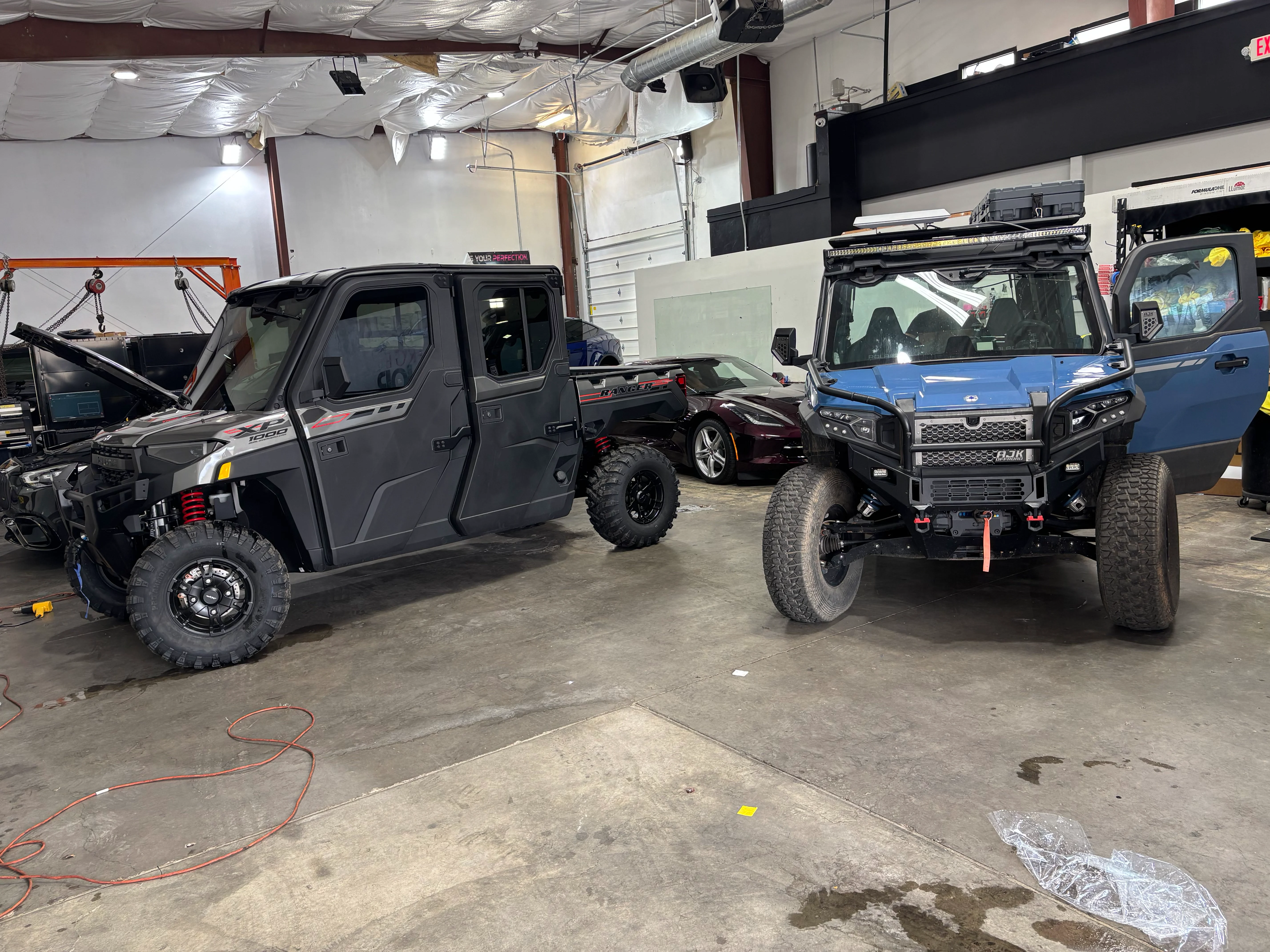 Two off-road vehicles (UTVs) inside a professional tint and PPF shop in St. George, Southern Utah, showcasing window tint.