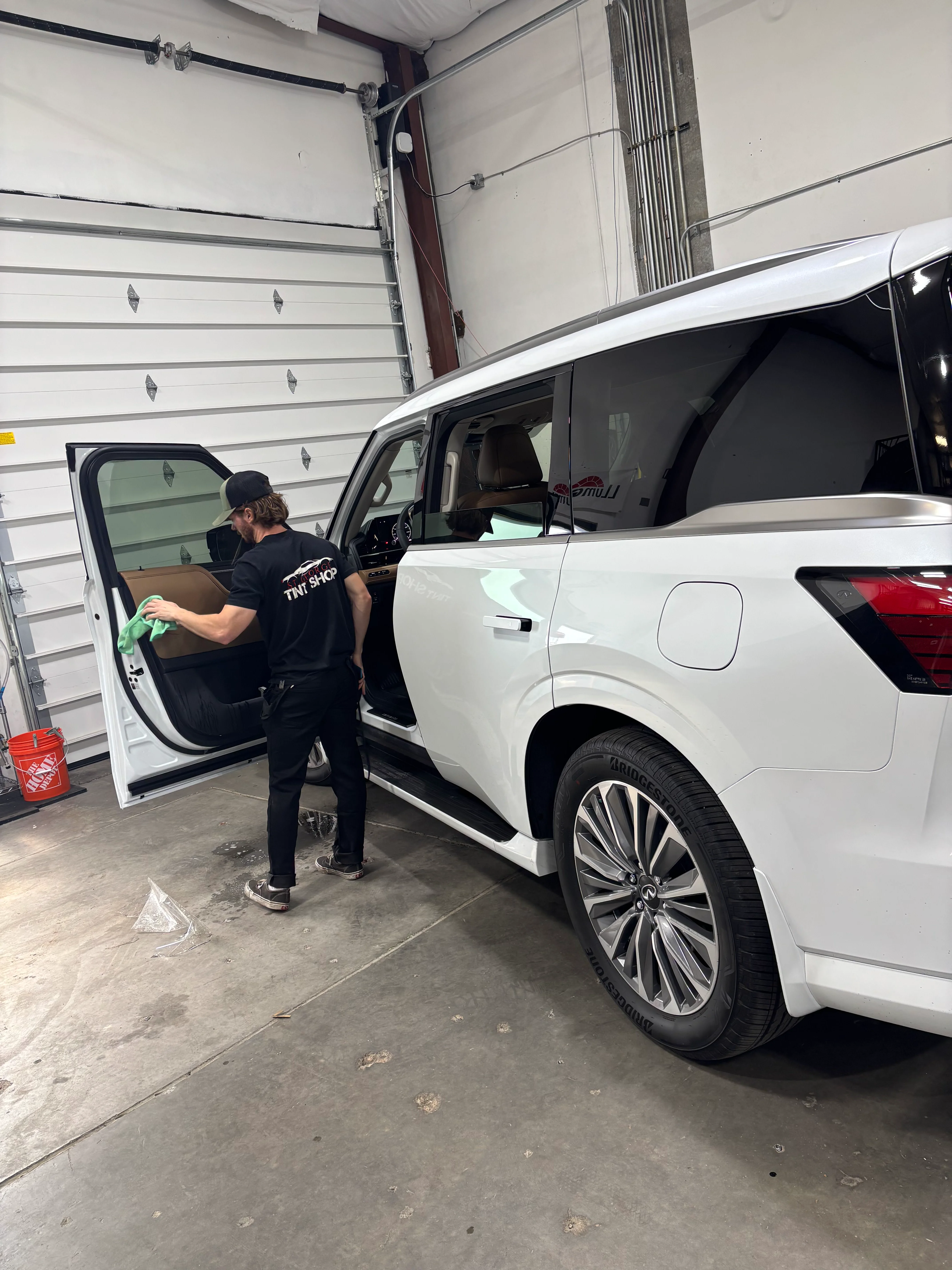 Tint technician cleaning interior of a white SUV with newly installed ceramic window tint in St. George, Southern Utah.