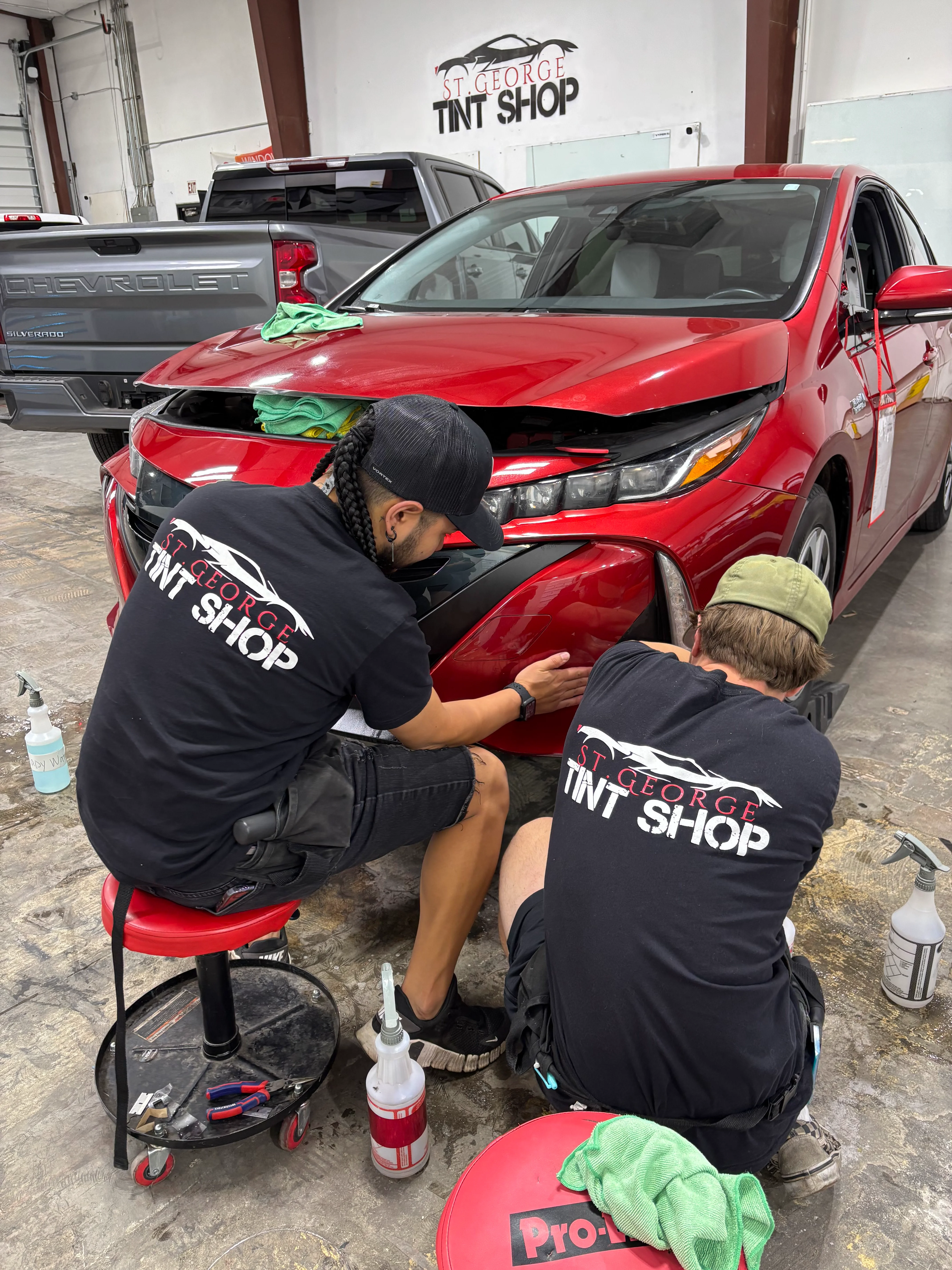 Skilled technicians apply PPF to the front bumper of a red sedan at a professional shop in St. George, Southern Utah.