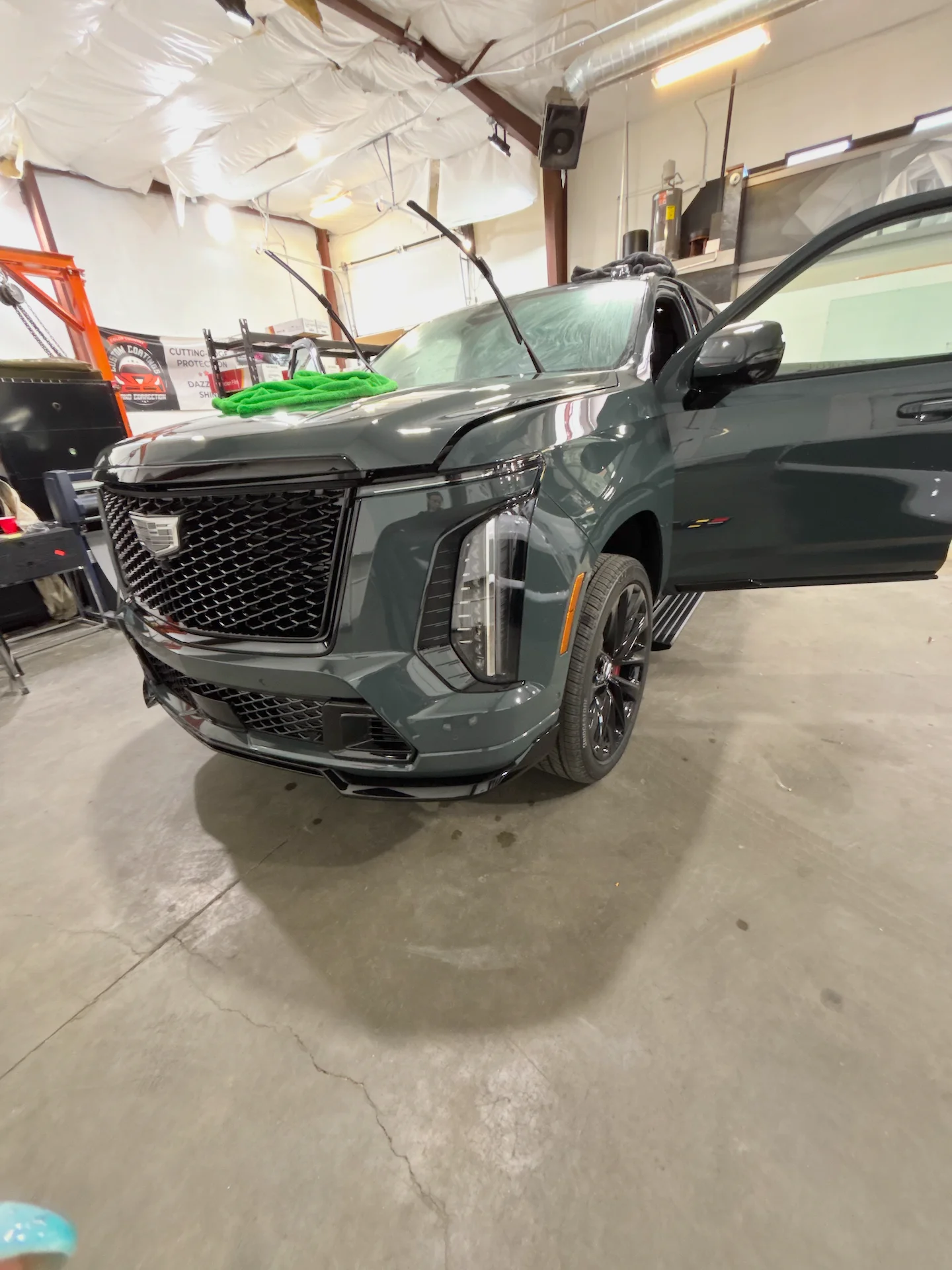 Dark green Cadillac Escalade SUV receiving precision ceramic window tinting at a professional shop in St. George, Southern Utah.